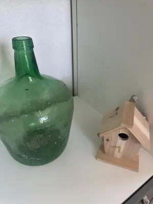 a green glass bottle and a bird house on a counter at La petite Chaumière in Bouilhonnac