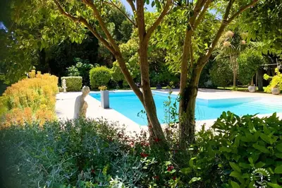 a woman standing next to a swimming pool in a garden at Gîte Jardin in Narbonne
