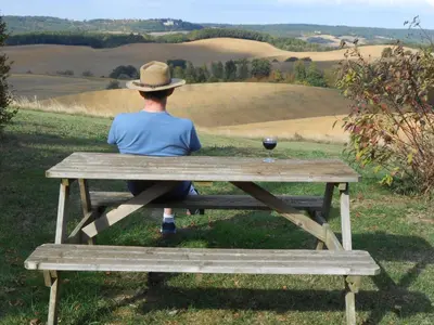 a person sitting on a picnic table with a glass of wine at Holiday Home Gemütliches Ferienhaus in Villautou by Interhome in Villautou