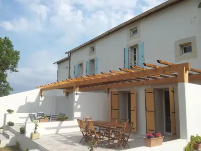 an external view of a house with a wooden table and chairs at Holiday Home Haus für 6 Personen und 8 Kinder in Villautou by Interhome in Villautou