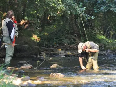 two men standing in a stream with a fishing rod at Mobil home 21m² avec terrasse à Axat - API-1-52-1082 in Axat