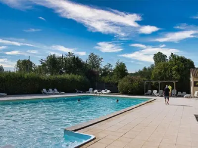 a person walking by a swimming pool at Mobil-home 2 chambres avec terrasse à Vielmur-sur-Agout - API-1-52-1324 in Vielmur-sur-Agout