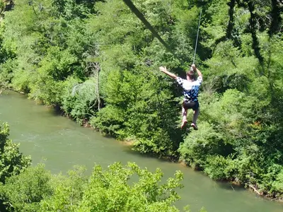 a person on a zip line over a river at Mobil-home cosy pour 2 à Pamiers - API-1-52-1959 in Pamiers