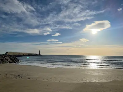 a beach with a pier and the ocean with the sun at Appt 4 personnes - balcon - 100 m plage in Port-la-Nouvelle