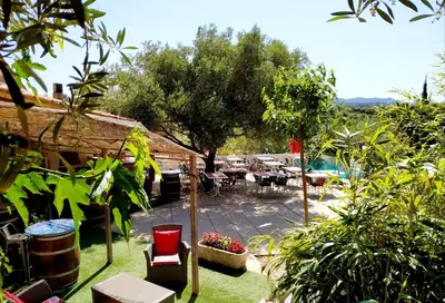 a garden with a patio with tables and chairs at Les chalets du Relais d'Aguilar in Tuchan