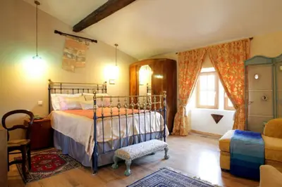 a bedroom with a bed and a chair at Maison de Textile Apartment in Montolieu