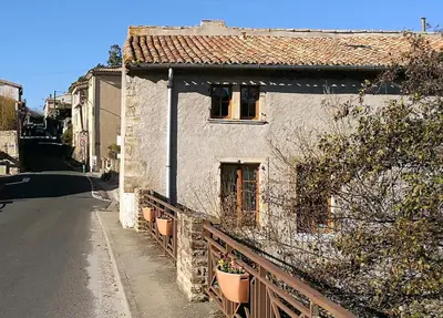 a white house with a fence next to a street at Maison de Textile in Montolieu