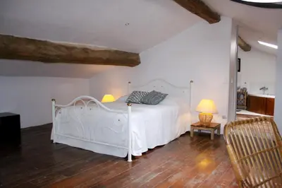 a bedroom with a white bed and a wooden floor at Chambres d'hôtes La Luciole in Tourtrol