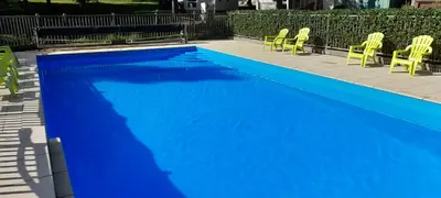 a blue swimming pool with yellow chairs next to it at Chalet et mobil homes dans la montagne au Camping les Sapins in Camurac