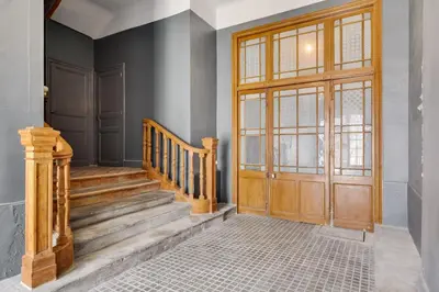 a hallway with a wooden door and stairs at TRIBUS-GITES URBAINS CARCASSONNE in Carcassonne