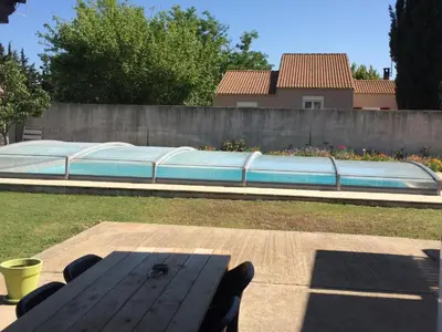 a picnic table in a backyard with a swimming pool at B & B Florence et Francis in Cuxac-dʼAude