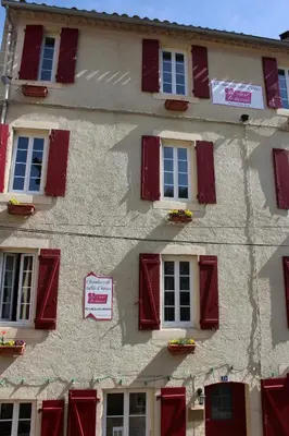 a building with red shutters and a sign on it at Au Coeur de Rennes Gîte in Rennes-les-Bains
