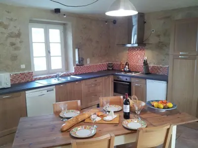 a kitchen with a wooden table with a bottle of wine at Domaine De Polfages in Villautou