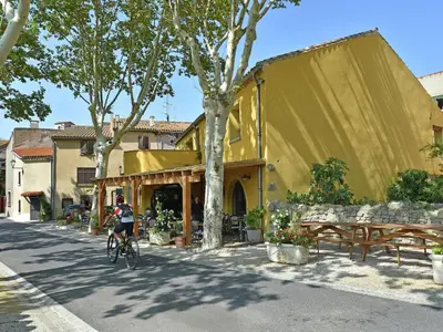 a person riding a bike in front of a yellow building at Blissful Stay in Mandourelle in Villesèque-des-Corbières