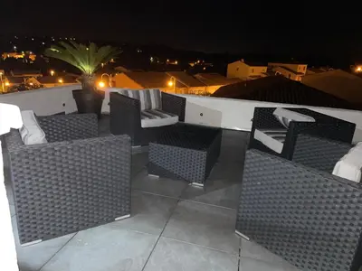 a group of wicker chairs on a balcony at night at Fun and sun room in Salles-d'Aude