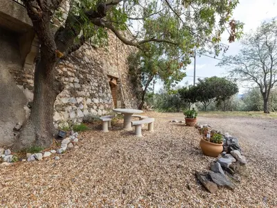a stone building with a picnic table and a tree at Holiday Home in Tautavel near Gorges de Gouleyrous in Tautavel