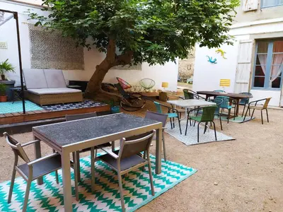 a group of tables and chairs under a tree at Le 9 de Cour, Chambre Chaco in Carcassonne