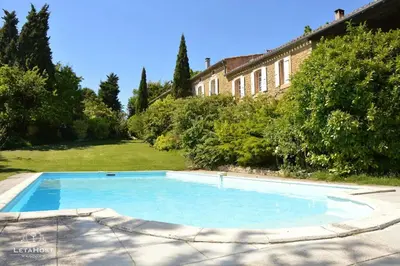 a large blue swimming pool in front of a house at Jardin Verdoyant à Soupex 