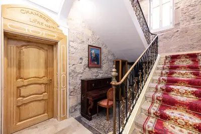 a staircase with a piano next to a stone wall at Studio Romantique Maison de L'église du Couvent in Narbonne