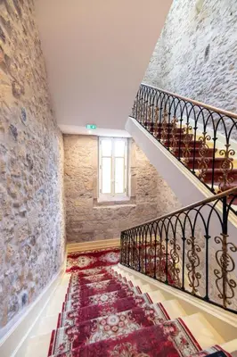 a staircase in a building with a stone wall at Chambre Lyre Maison de L'Église du Couvent in Narbonne