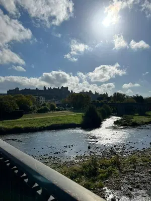 a bridge over a river with the sun in the sky at Le Bout du Monde Appartement Hyper-centre in Carcassonne