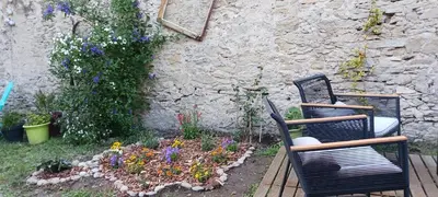 two chairs and a flower garden in front of a building at Le 9 de Cour, Chambre Kiwi in Carcassonne