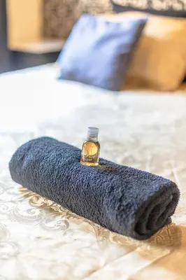 a blue blanket on a bed with a bottle of perfume at Charmant Studio Baignoire in Narbonne