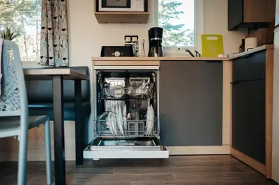 a dishwasher with dishes in it in a kitchen at Mobil Home XXL 4 chambres - Camping Le Barberousse in Gruissan