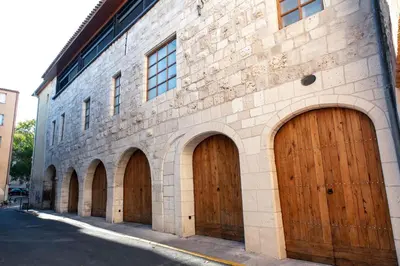a brick building with four brown wooden garage doors at Chambre Familiale Maison de L'Église du Couvent in Narbonne