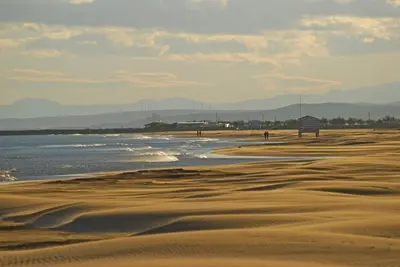 a beach with sand and water with mountains in the background at Escale à Gruissan au coeur de la Marina in Gruissan