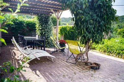 a patio with a table and chairs under a pergola at Côté Vignes à Bélesta in Bélesta