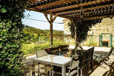 a table and chairs under a wooden pergola at Côté Vignes à Bélesta in Bélesta