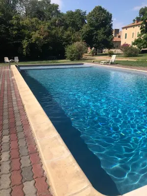 a swimming pool with blue water in a yard at Gîte Superbe L'Ecurie XIXème in Sallèles-dʼAude