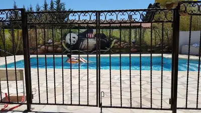 a gate with a panda bear laying next to a pool at Tranquillité B&B in Cuxac-dʼAude