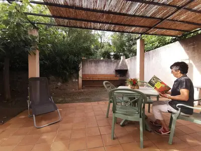 a woman sitting at a table under a pergola at Lou soula in Trilla