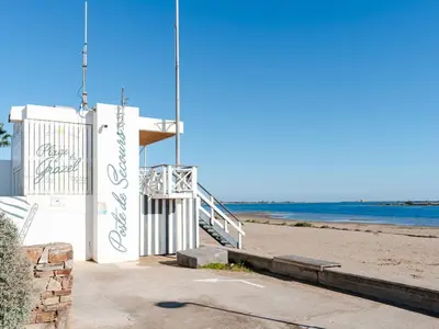 a building on the beach with the ocean in the background at Pavillon lumineux avec terrasse, à 1 km de la plage – 2 pièces, 1 chambre, barbecue, Wi-Fi - FR-1-409A-3 in Gruissan