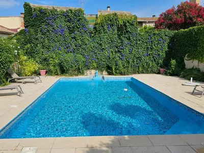 a swimming pool with an umbrella and two chairs and a table and an umbrella at OCC34 - Capestang - Vigneron in Capestang