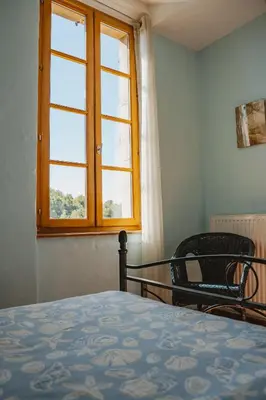 a bedroom with a bed and a window and a chair at Le Relais de Tamaroque in Portel-des-Corbières