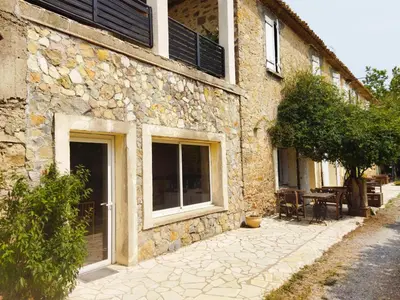 a stone building with windows and a table outside at Aur Blan - Les Pipistrelles in Le Somail