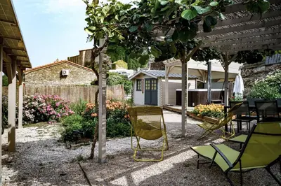 a patio with chairs and a table under a tree at Côté Grange à Bélesta in Bélesta